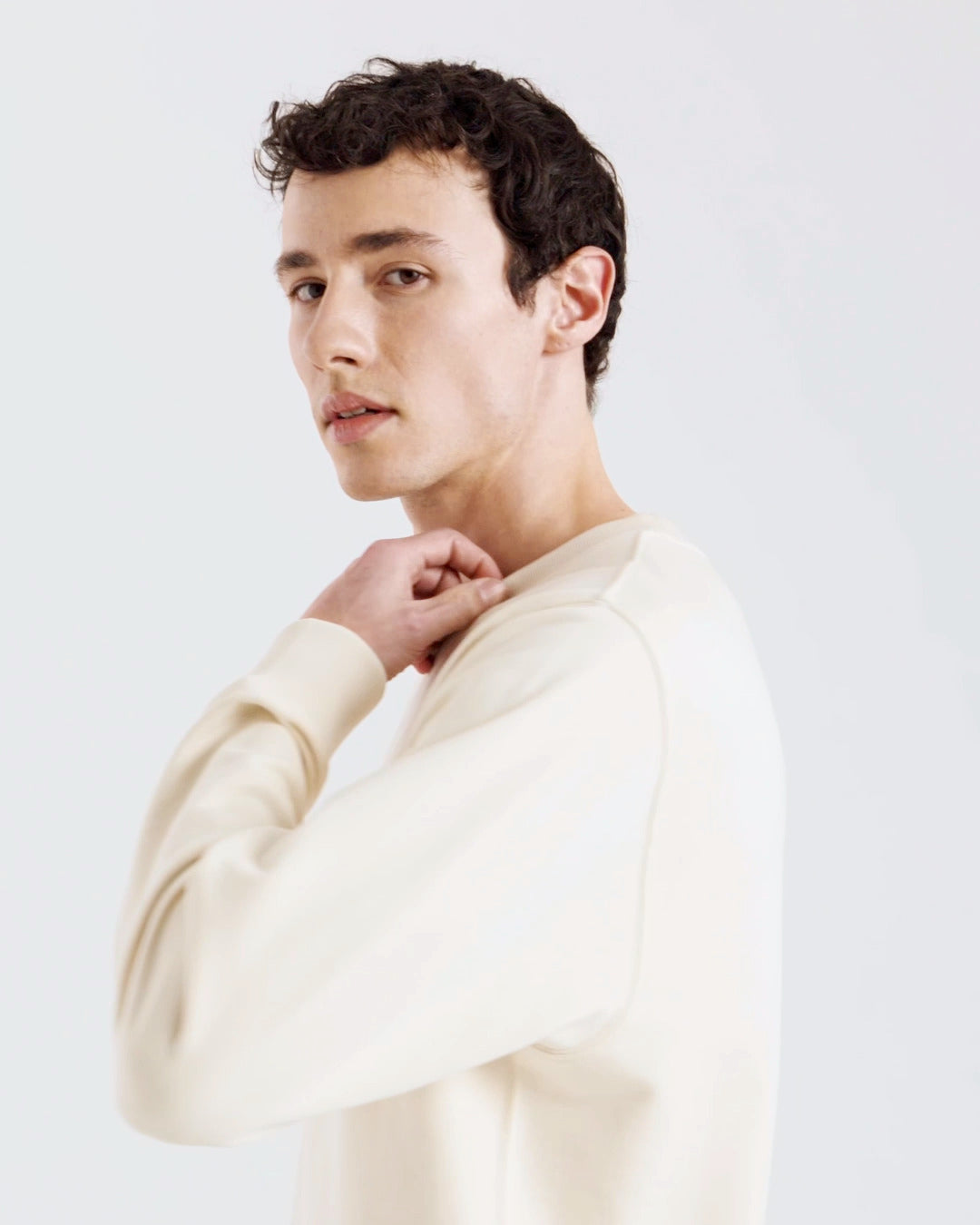 A compilation of short video clips, of a man modelling a plain natural coloured, organic cotton sweatshirt, with a pair of jeans.