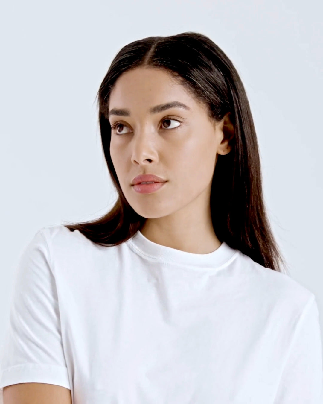 A compilation of short video clips of a woman modelling a plain white, organic cotton t shirt with a pair of jeans.