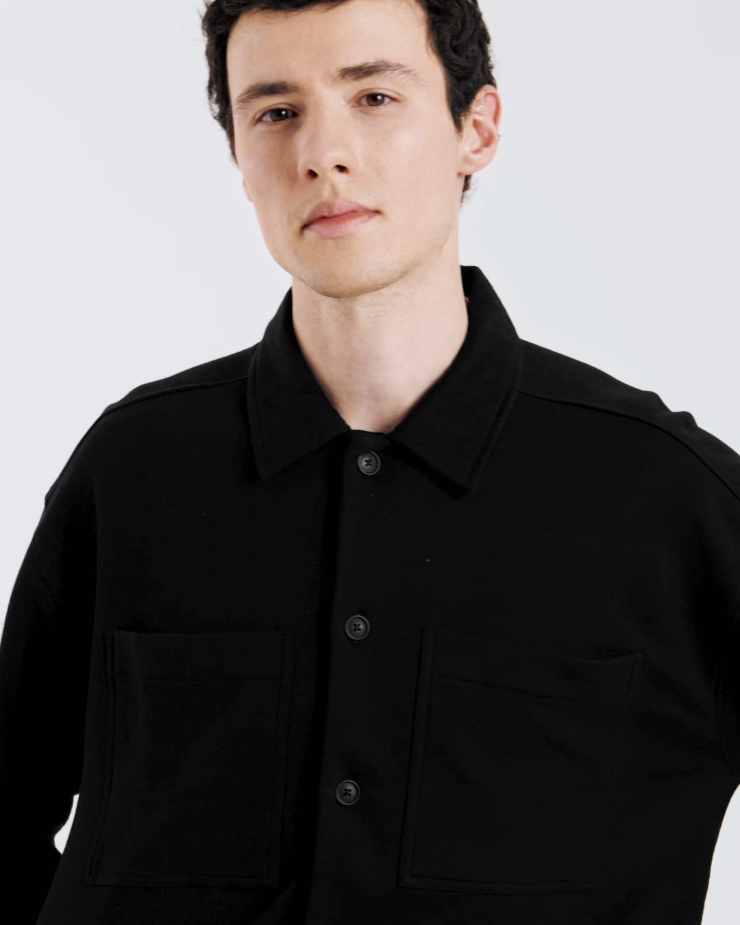 A compilation of short video clips of a man modelling plain black, organic cotton overshirt with a pair of jeans.